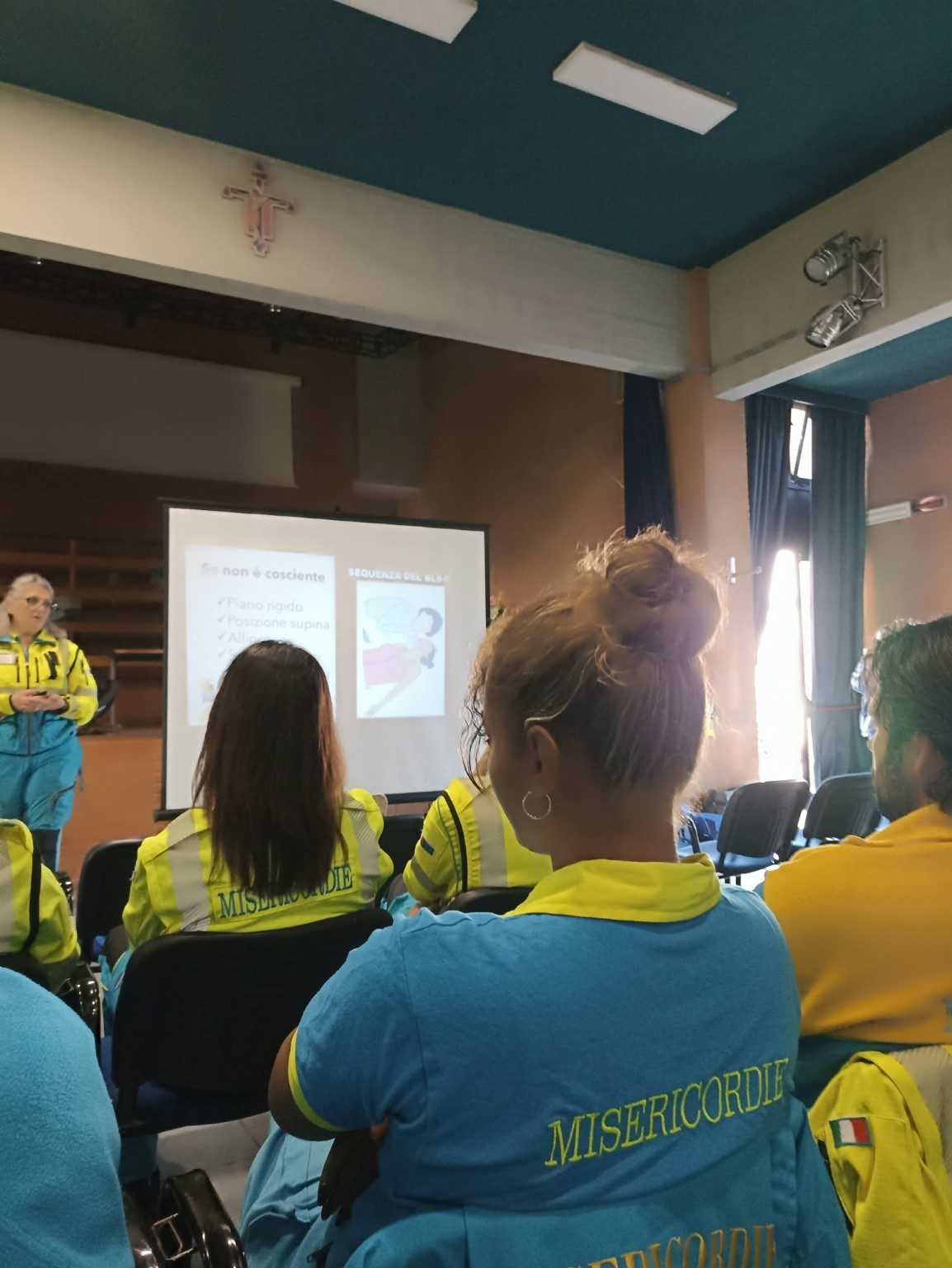 Volontari della Misericordia di Ariccia, in divisa gialla e ciano, seguono la lezione in aula davanti allo schermo durante il corso del 25 ottobre 2026.