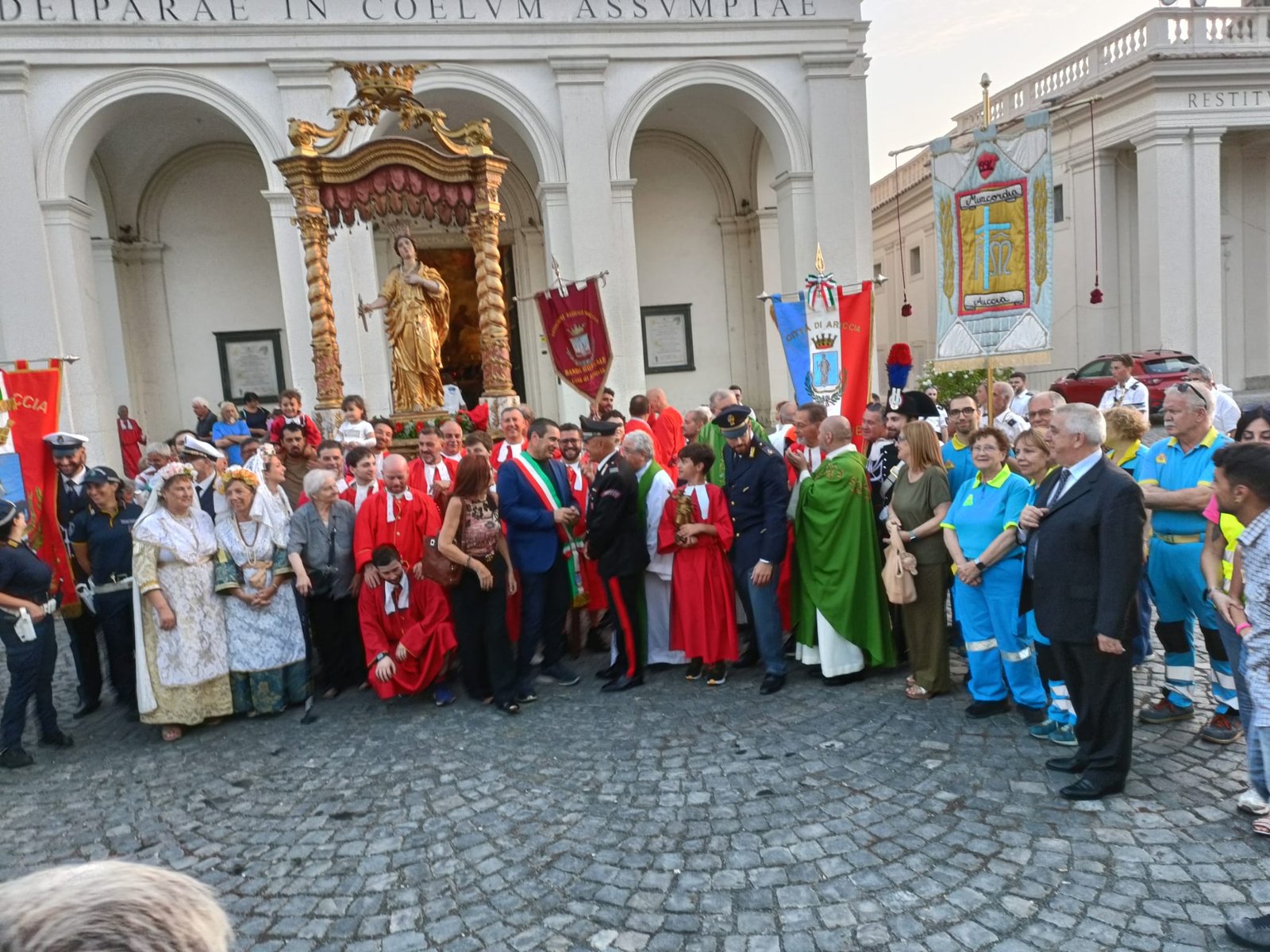 Foto di gruppo davanti all'Assunta: la statua della Santa, i Cavalieri, il Sindaco, le autorità, i costumi tradizionali e i volontari della Misericordia con lo stendardo