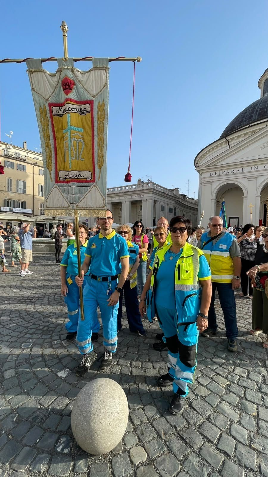 Il confratello della Misericordia regge lo stendardo della Confraternita, datato 1996, in Piazza di Corte