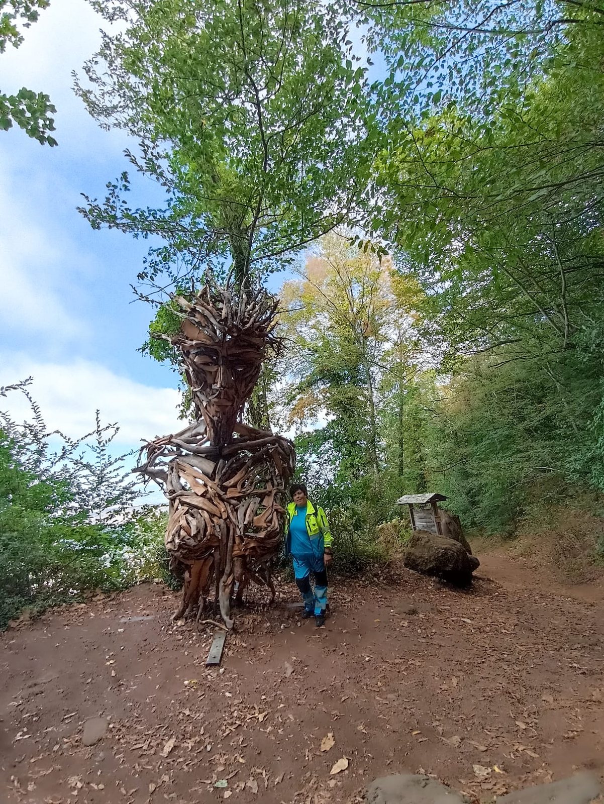Una volontaria della Misericordia in divisa accanto a Flora, la gigantesca scultura in legno di recupero di Marco Martalar lungo il sentiero verso Monte Cavo