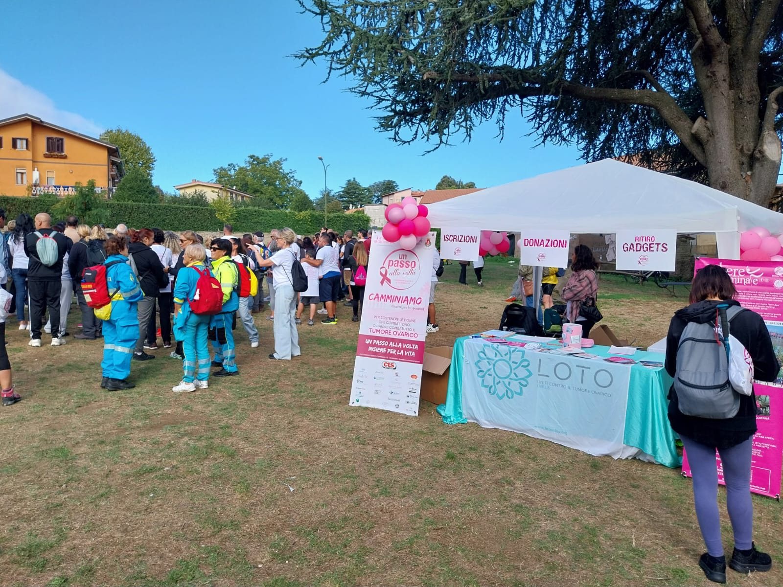 Il ritrovo al Parco La Pompa: il gazebo con iscrizioni, donazioni e ritiro gadget, il banchetto di Loto OdV, il roll-up rosa «Un passo alla volta» e i volontari della Misericordia con gli zaini tra i partecipanti