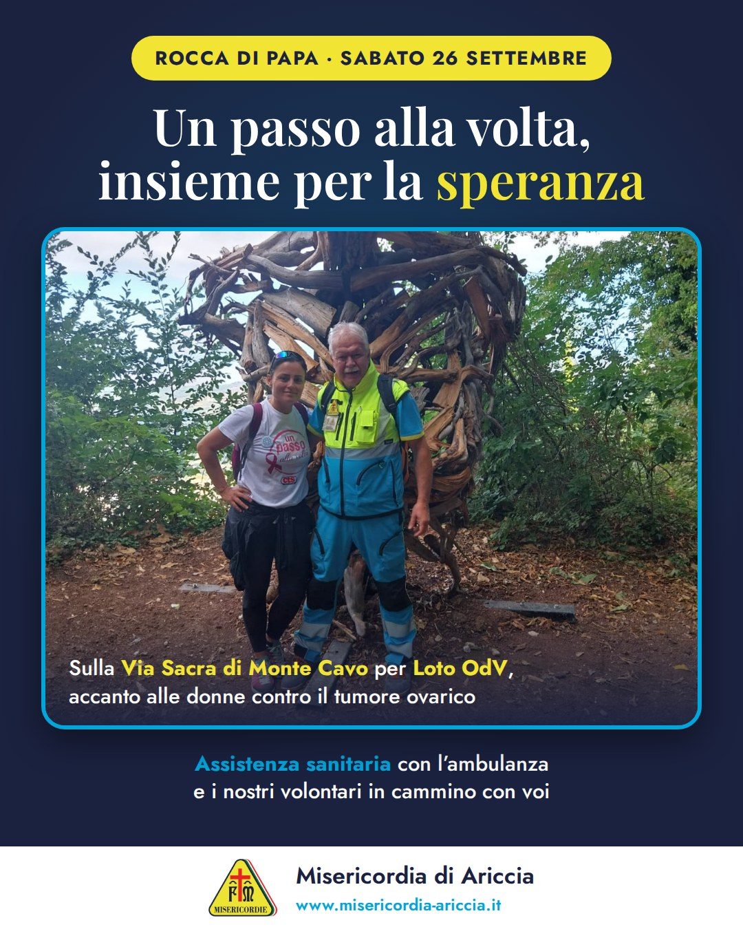 Grafica della Misericordia di Ariccia «Un passo alla volta, insieme per la speranza»: un volontario in divisa e una partecipante con la maglietta dell’evento davanti alla scultura in legno Flora, sulla Via Sacra di Monte Cavo, il 26 settembre 2026