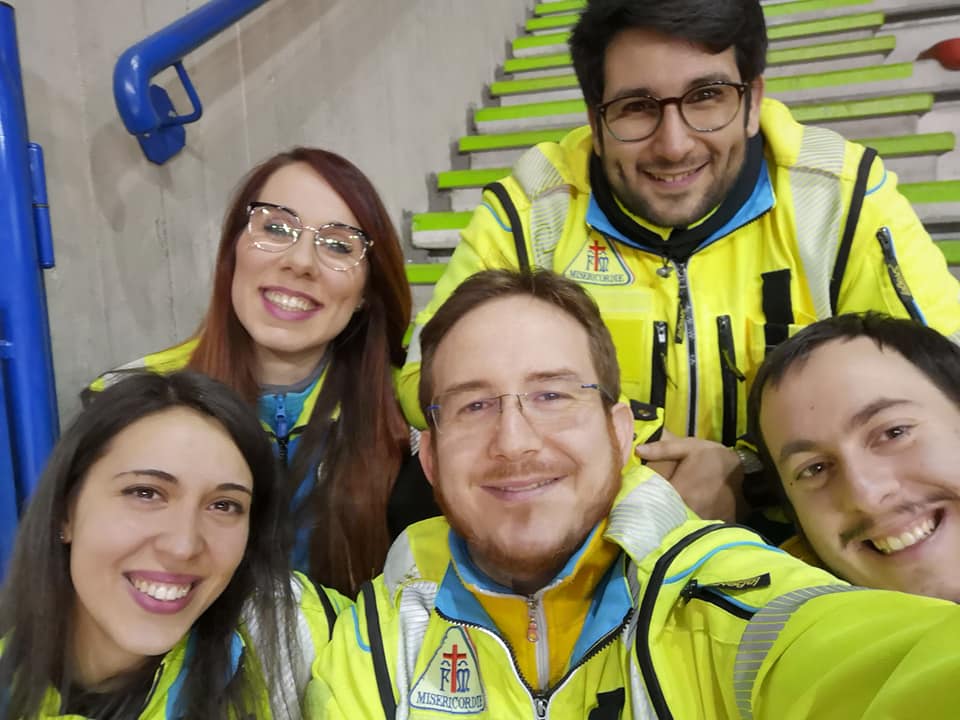 Selfie di un equipaggio di volontari della Misericordia di Ariccia sorridenti, con la divisa giallo-ciano